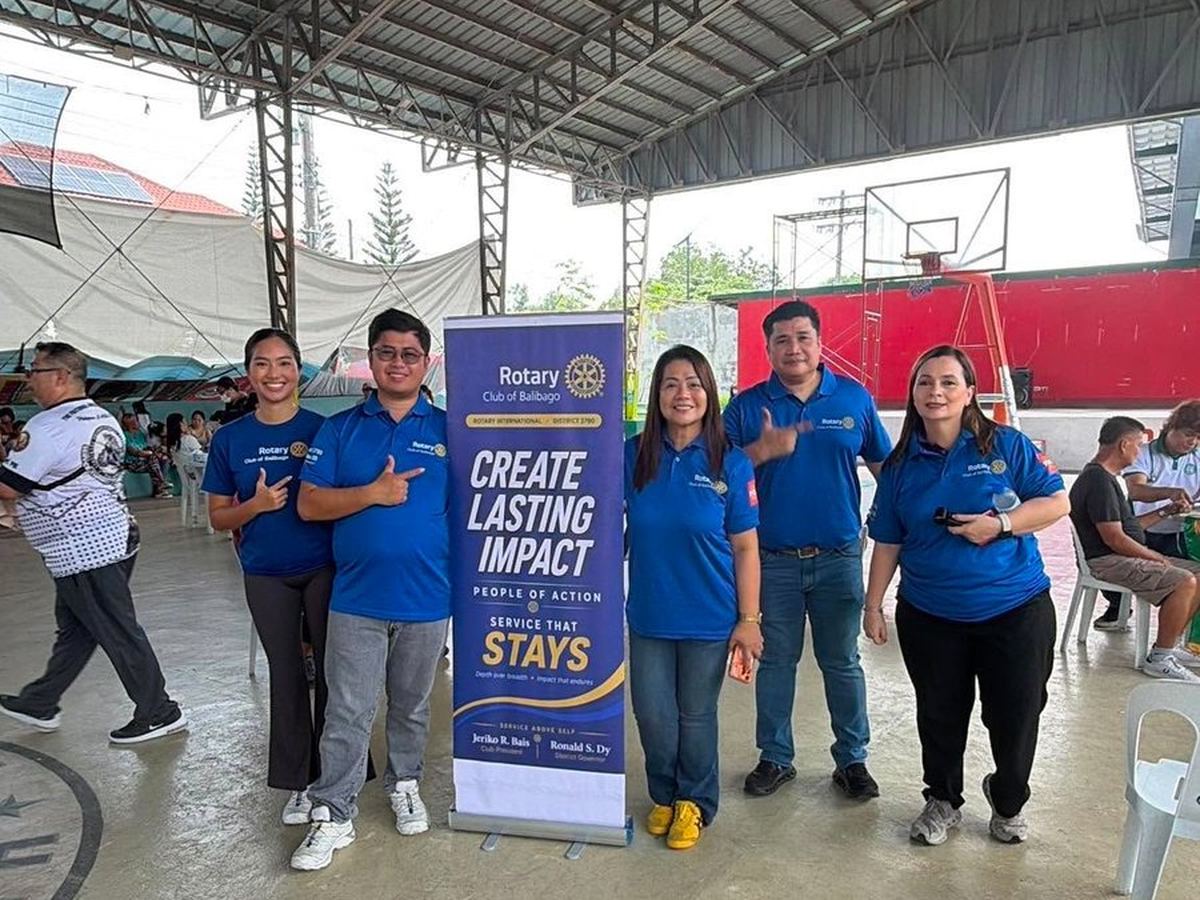 Members beside the Service That Stays standee at the medical mission