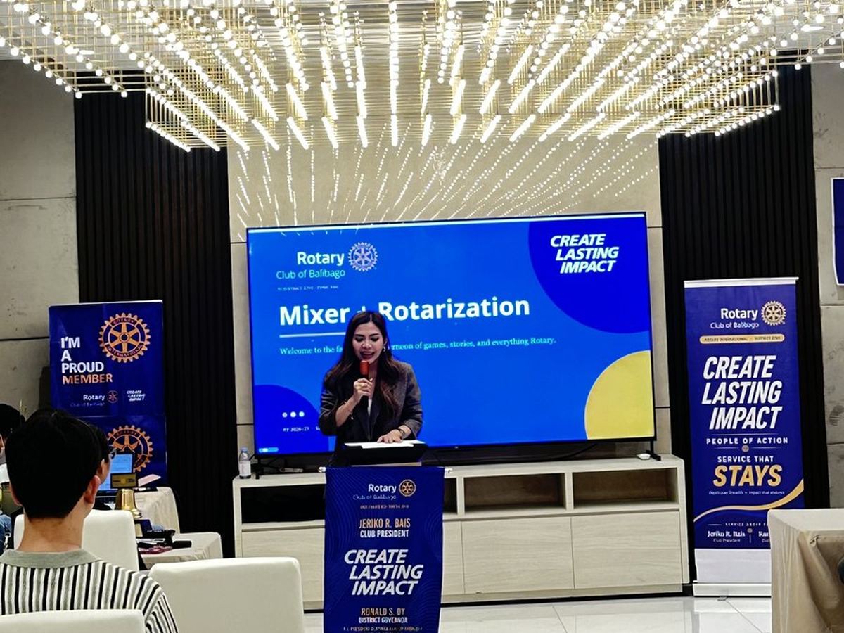A speaker at the podium beside the Mixer and Rotarization slide